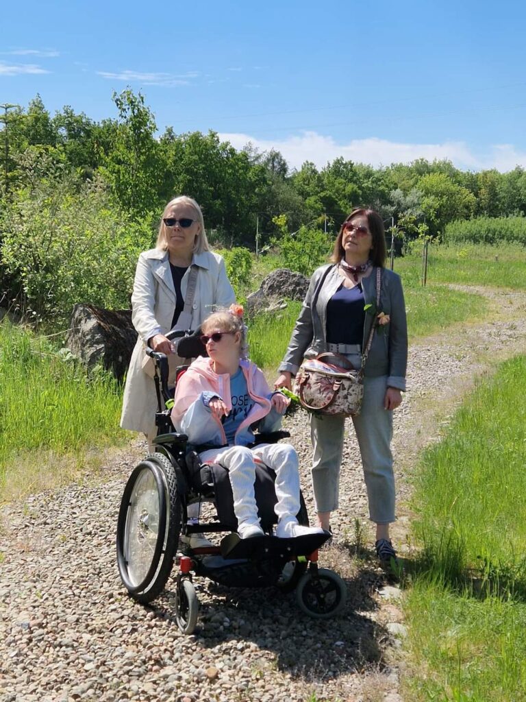 dwie kobiety i dziewczynka na wózku inwalidzkim