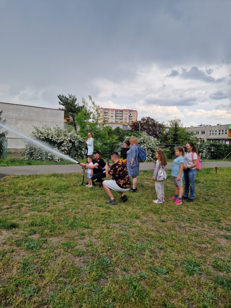 dzieci i strażak z chłopcem lejący wodę