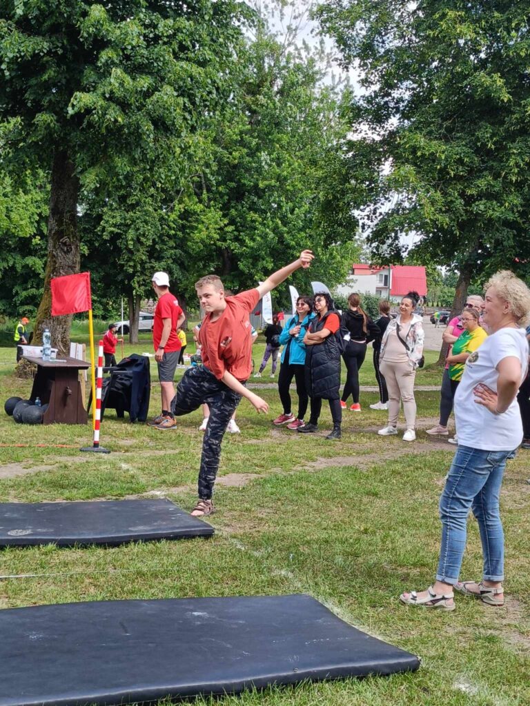 chłopak stojący na jednej nodze i grupa ludzi patrząca w dal