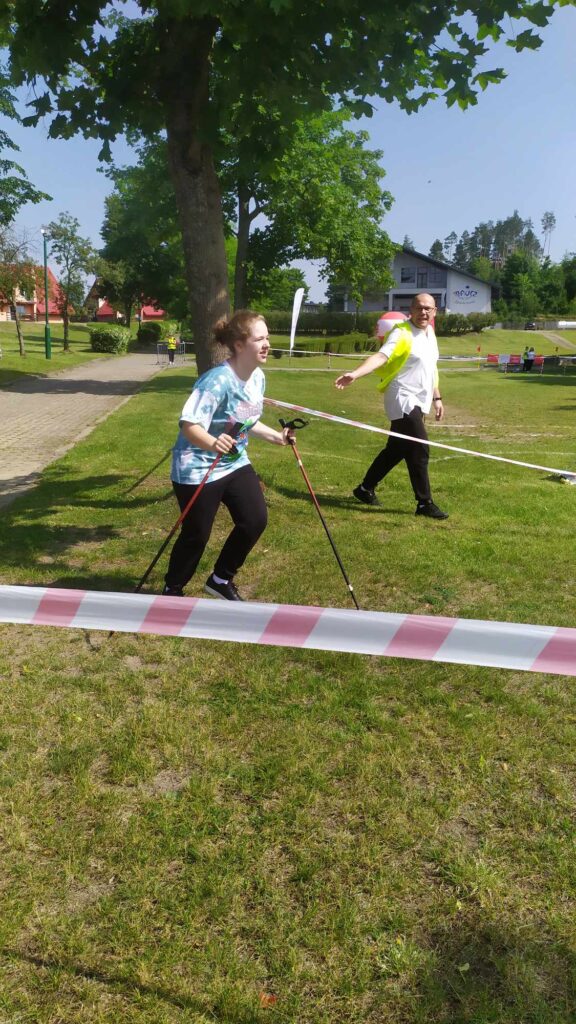 Dziewczynka z kijami do nordic walking biorąca udział w konkurencji chodzenia