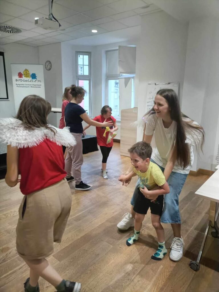 bawiące się dzieci i wolontariusze ze skrzydłami na plecach