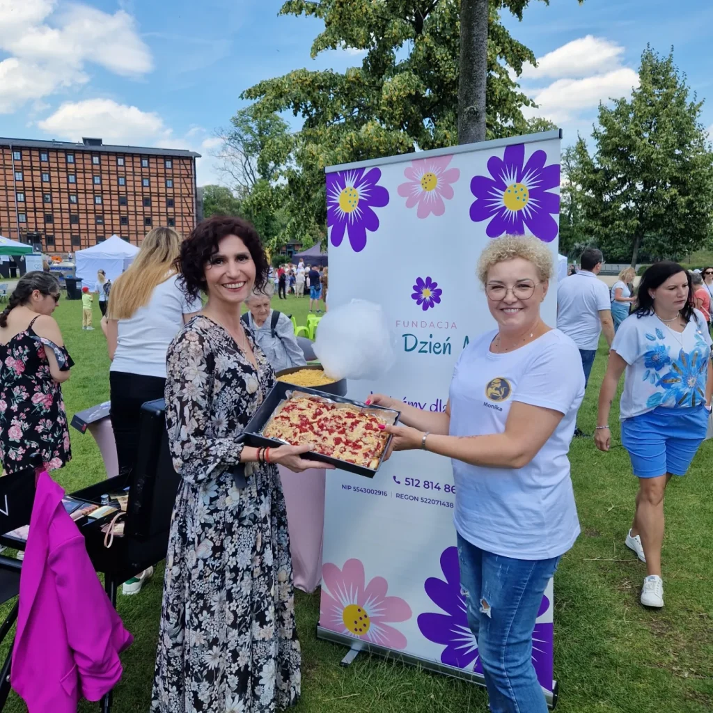 Joanna z fundacji piękny dzień mamy trzymająca ciasto wraz z Moniką z fundacji mokkka