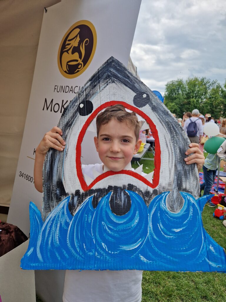 chłopiec pozujący do zdjęcia jako rekin a w tle rollup fundacji mokkka