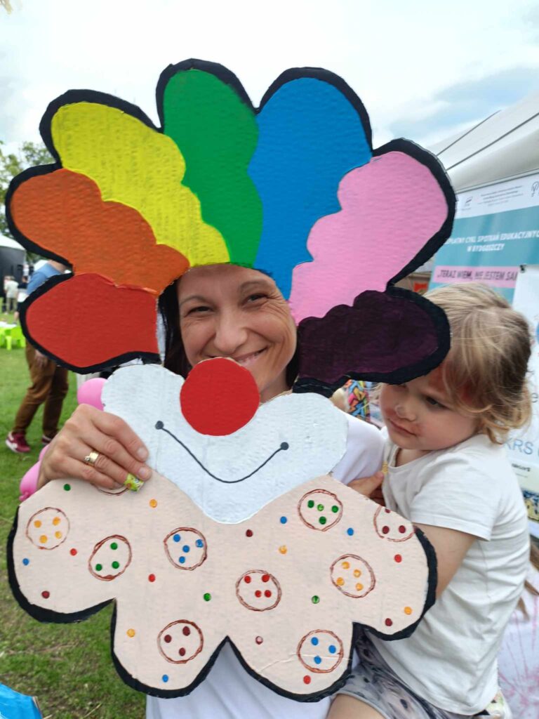 kobieta pozująca do zdjęcia jako klaun trzyma na ręku dziewczynkę