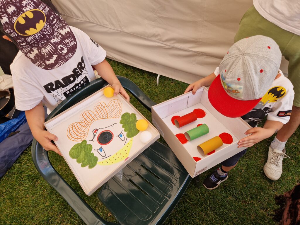 dzieci grające w gry z kartonów , celują piłeczką aby trafić do dziury